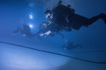 open water students working on buoyancy and trim in the pool during a padi open water diver course